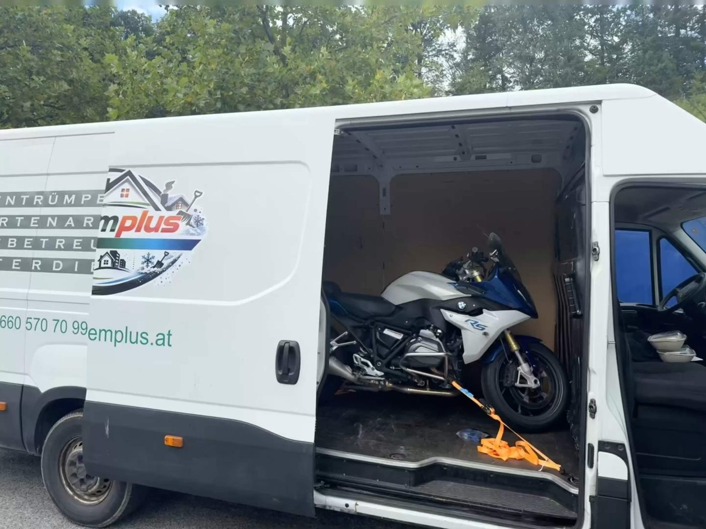 Offene Schiebetür des Transporters, Ladung mit Spanngurt gesichert